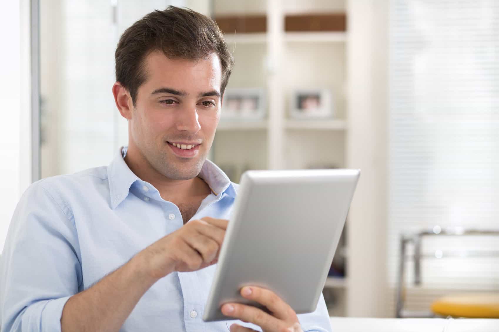 Man using tablet pc on couch at home iPad service